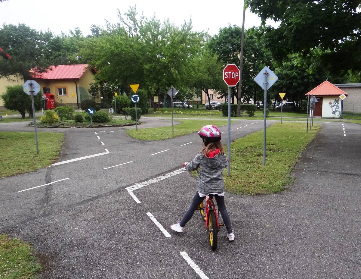 Na zdjęciu dziewczynka w kasku na rowerku podczas jazdy na edukacyjnej ścieżce rowerowej