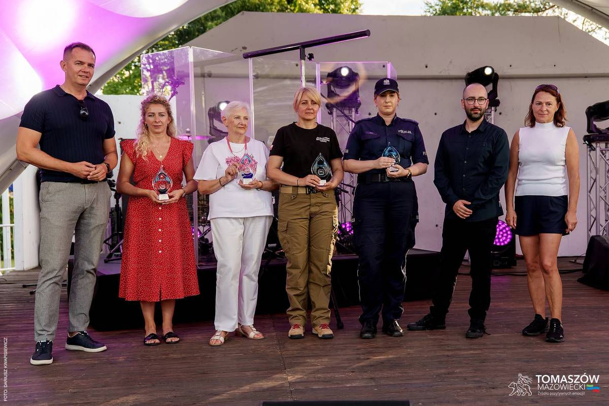 Na scenie wiceprezydent Tomaszowa Mazowieckiego z laureatami Konkursu Kreatywności Społecznej „Lokalni Niebanalni” oraz współorganizatorami konkursu. Nagrodzeni trzymają w rękach statuetki.