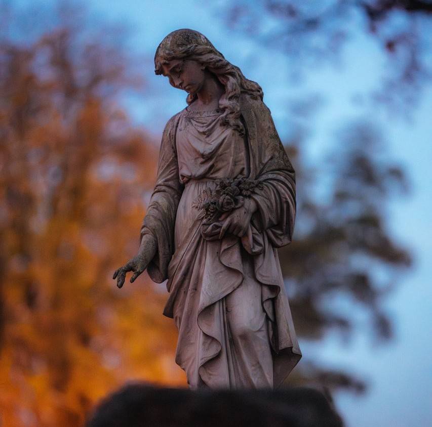 Na zdjęciu figura sakralna przedstawiającego dziewczynę  w sukni na jednym z grobów na tomaszowskim cmentarzu rzymsko-katolickim