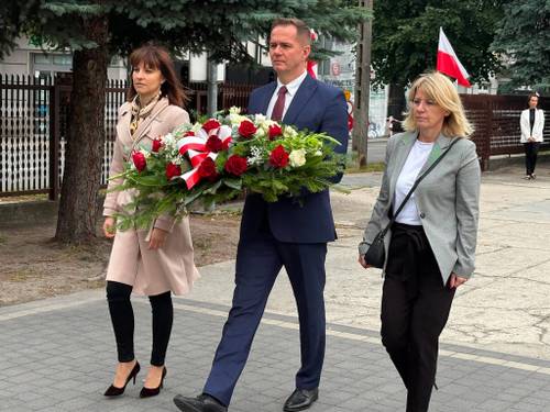 Delegacja władz miasta składa kwiaty pod Pomnikiem Nieznanego Żołnierza. Zastepca prezydentav w asyście sekretarz miasta i skarbniczki miasta niesie wiązankę biało-czerwonych kwiatów