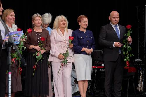 Na scenie nagrodzeni nauczyciele i dyrektorzy z czerwonymi różami, obok stoją prezydent miasta i przewodnicząca Rady Miejskiej