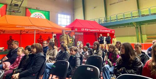 Krajowego Treningu Rodzinnego Akademii Ochrony Ludności i Obrony Cywilnej, który odbył się w Szkole Podstawowej nr 1 w Tomaszowie Mazowieckim. Wśród słuchaczy całe rodziny. W tle namioty stanowisk edukacyjnych.