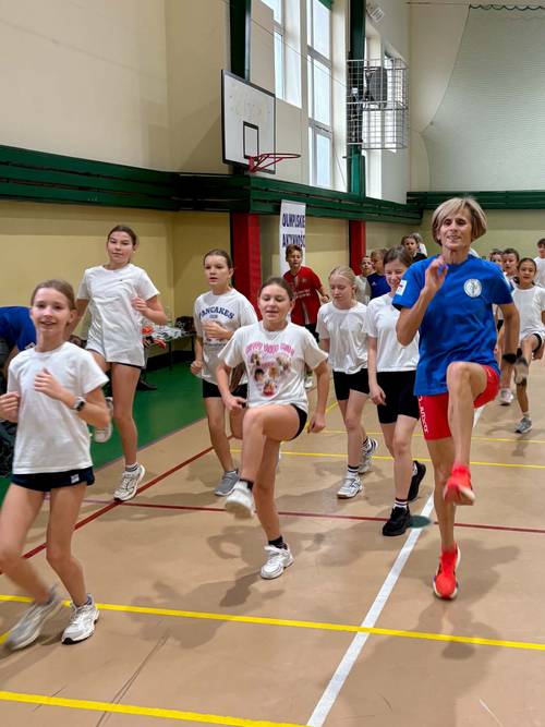 Uczniowie ćwiczą z Olimpijką Wandą Panfil, która prowadzi trening ogólnorozwojowy na sali gimnastycznej w Szkole Podstawowej nr 6