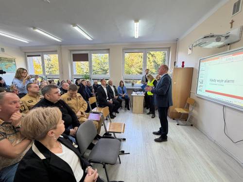 Dyrektor Wydziału Zarzadzania Kryzysowego omawia przed uczestnikami ćwiczeń w klasie lekcyjnej ich przebieg i organizację